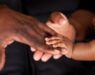 mother and infant holding hands with brown skin